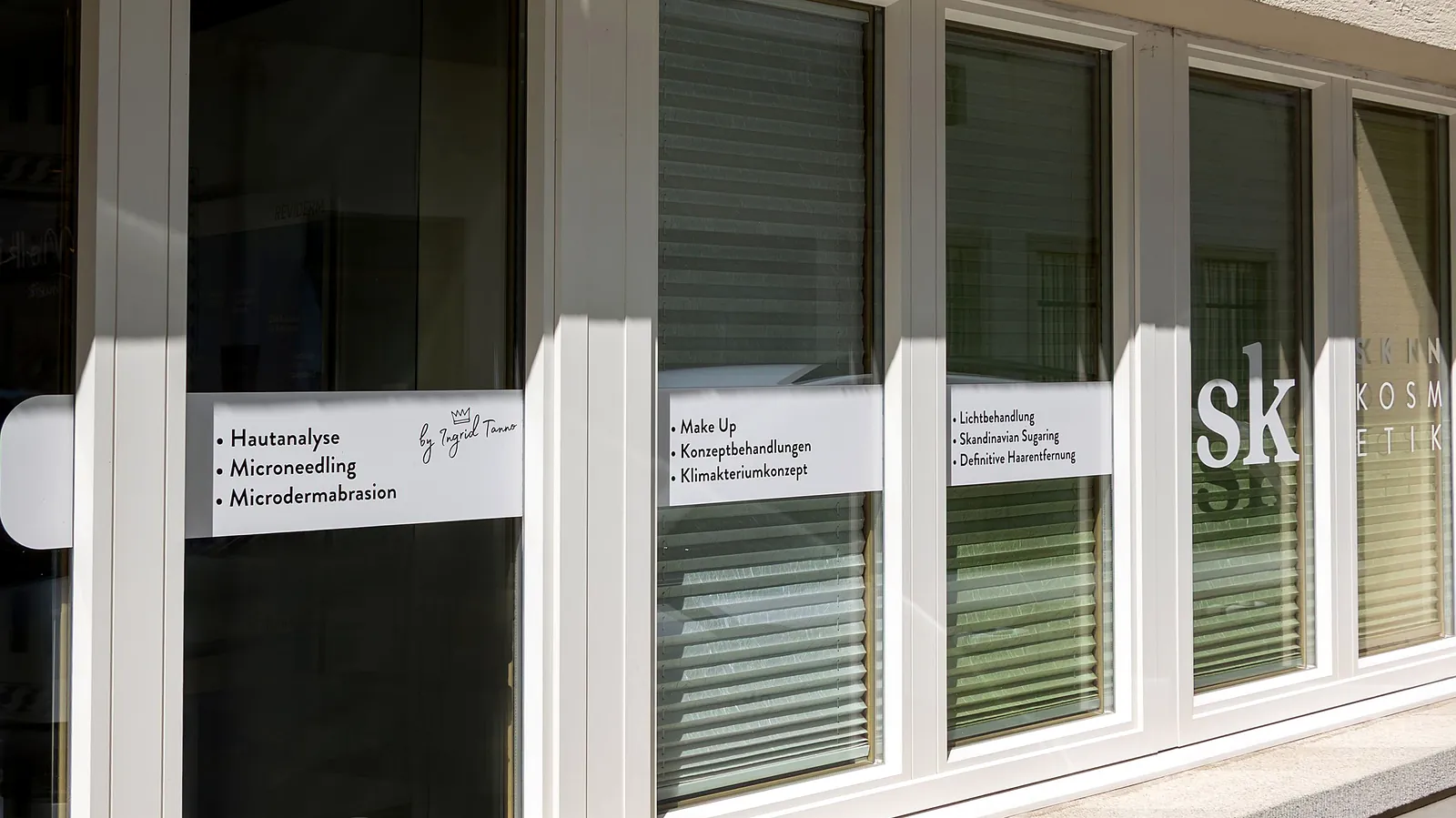 Schaufenster von Skin Kosmetik mit dem sk Logo und der Liste der Behandlungen