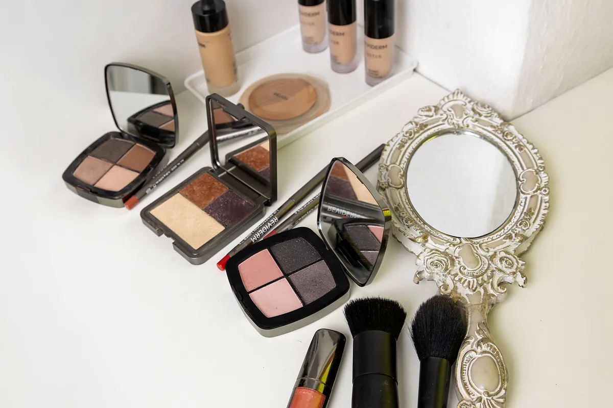 Make-up Paletten, Pinsel und ein Handspiegel im Studio